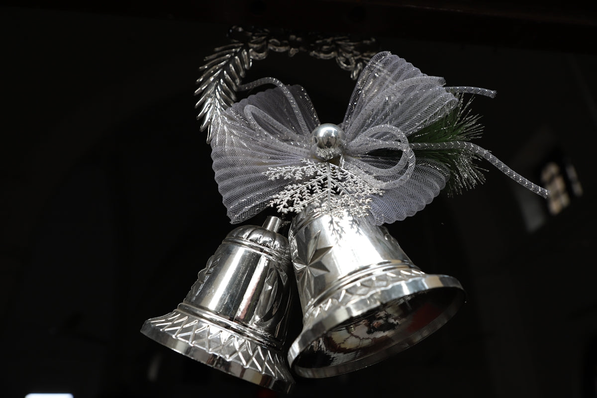 a silver bell with a bow hanging from it's side